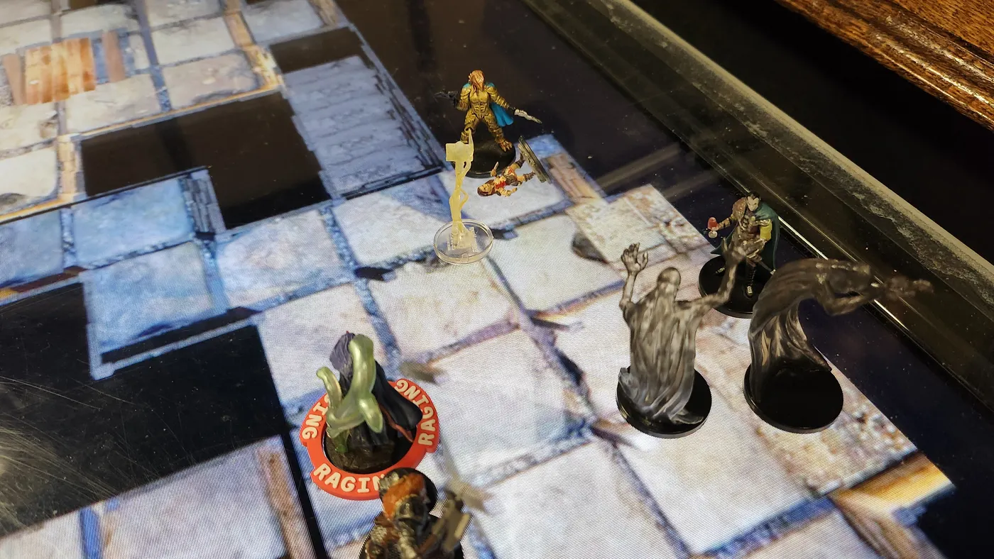 Painted miniatures on a glowing digital battle map, mid-fight